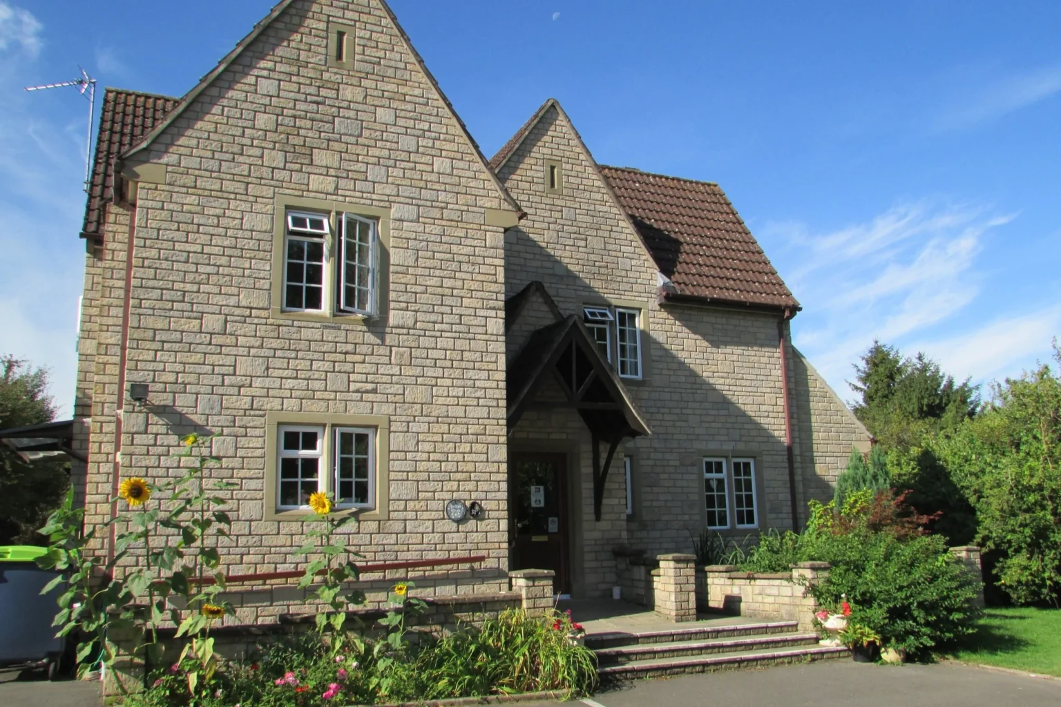 A warm, sunlit English care home with sunflowers in the garden